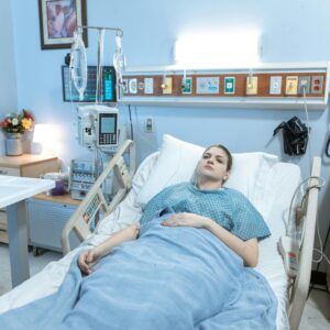 A young woman lies in a hospital bed during her recovery process in a calm, well-equipped room.